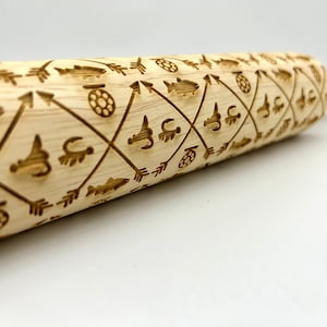 May include: A wooden rolling pin with a repeating pattern of fish, arrows, and fishing lures. The rolling pin is made of light wood and has a natural finish.