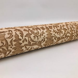 May include: A wooden rolling pin with a detailed engraved design of Christmas trees, reindeer, and snowflakes. The rolling pin is made of natural wood and has a light brown color.