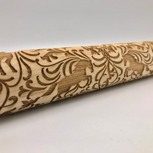 May include: A wooden rolling pin with a carved design of horses and floral patterns. The rolling pin is light brown in color and has a smooth surface.