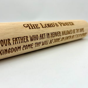 May include: A wooden rolling pin with the Lord's Prayer engraved on it. The text reads "THE LORD'S PRAYER OUR FATHER WHO ART IN HEAVEN, HALLOWED BE THY NAME THY KINGDOM COME THY WILL BE DONE ON EARTH AS IT IS IN HEAVEN."