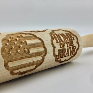 May include: Wooden rolling pin with an engraved American flag and the words "Home of the Brave" in a cloud shape.