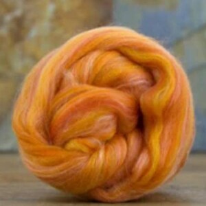 May include: A ball of orange, yellow, and white merino wool roving. The roving is soft and fluffy, and it is perfect for spinning or felting.