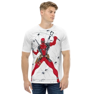 Könnte beinhalten: Weißes T-Shirt mit einem vollfarbigen Druck von Deadpool in Kampfpose. Der Hintergrund ist weiß mit schwarzen Rissen und kleinen schwarzen Spinnen.
