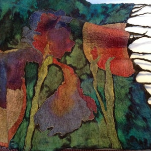 May include: A felted scarf with a floral design. The scarf features large, stylized flowers in shades of red, purple, and orange against a green and blue background. The edges of the flowers are outlined in gold.