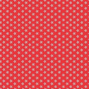 Op de afbeelding: Rode stof met een herhalend patroon van kleine, witte, zesbladige bloemvormen. De stof heeft een liniaal langs de onderrand, gemarkeerd in inches, met de tekst "Riley Blake Designs".