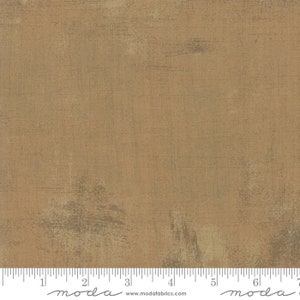 May include: A close-up of a brown fabric with a subtle textured pattern. The fabric has a slightly distressed look with a hint of green throughout. The fabric is measured in inches with a ruler at the bottom of the image. The ruler has the word "moda" printed on it.