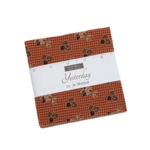 May include: A stack of fabric squares with a repeating floral pattern in shades of brown and tan. The fabric is wrapped with a white band that reads "Yesterday by Jo Morton."