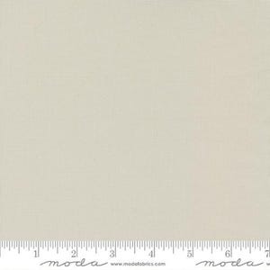 May include: A solid, off-white fabric with a subtle texture. The fabric is smooth and has a slightly sheen finish. The fabric is shown with a ruler for scale.