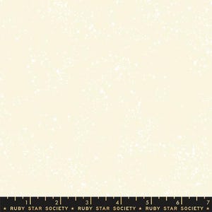 Op de afbeelding: Crèmekleurige stof met een gespikkeld patroon. De stof heeft een subtiele textuur met kleine witte vlekken verspreid over het oppervlak. De onderrand heeft een zwarte liniaal met de tekst "RUBY STAR SOCIETY".