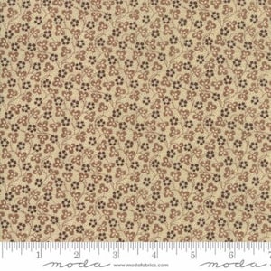 May include: A beige fabric with a brown floral pattern. The fabric is covered in small brown flowers with a repeating pattern. The fabric is measured with a ruler in inches.