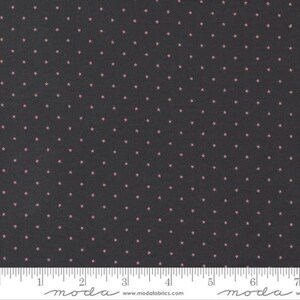 May include: Black fabric with a repeating pattern of small pink stars. The fabric is shown with a ruler for scale.