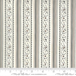May include: White fabric with a repeating pattern of vertical stripes in shades of gray and pink. The stripes are accented with a delicate floral design in gray. The fabric is labeled "moda" and includes a ruler for scale.