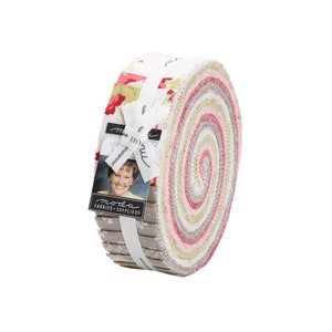 May include: A roll of fabric featuring a variety of floral prints in shades of pink, green, and gray. The fabric is rolled up and tied with a white ribbon. The label on the fabric reads "moda fabrics & supplies".