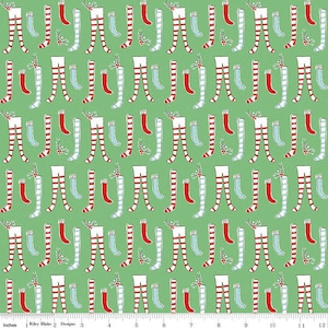 May include: Green fabric with a repeating pattern of red and white striped stockings and blue and white striped socks. The stockings and socks are arranged in a symmetrical pattern.