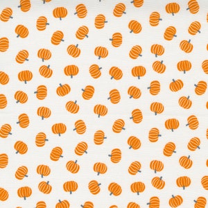 May include: A white fabric with a repeating pattern of orange pumpkins. The pumpkins are all the same size and shape, and they are arranged in a random pattern.