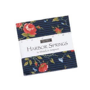 May include: A stack of fabric squares with a floral pattern featuring red roses and blue accents on a navy blue background. The fabric is labeled "Harbor Springs" by Minick & Simpson.
