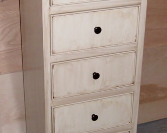 May include: A tall, narrow chest of drawers featuring five stacked drawers with small, round, black knobs. The frame is finished in a distressed off-white paint, while the flat top surface is a contrasting dark brown wood with a smooth finish.