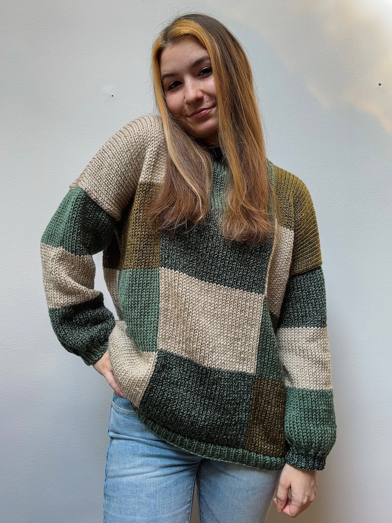 May include: A green, brown, and beige color block sweater with a relaxed fit.