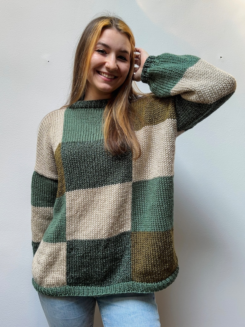 May include: A green, beige, and brown color block knit sweater with a crew neck and long sleeves.