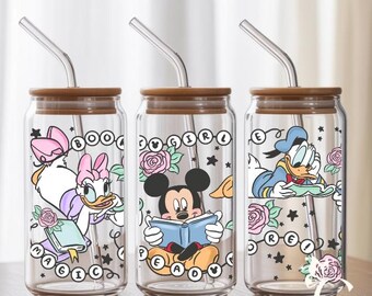 May include: Three clear glass drinking jars with brown lids and curved metal straws. Each jar features a different Disney character: Daisy Duck, Mickey Mouse, and Donald Duck. The jars are decorated with floral and star accents, and the words "BOOK GIRL MAGIC" are printed on the jars.