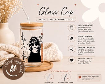 May include: A 16oz clear glass cup with a bamboo lid and a glass straw. The cup features a black graphic illustration of a person with sunglasses and the text Taylor Swift and Speak Now. The design includes small floral accents in red and orange.