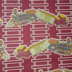May include: A red background with a repeating pattern of yellow and white train cars. The train cars are blue, red, and yellow with black wheels. The train cars have the letters "T & L" on the side.