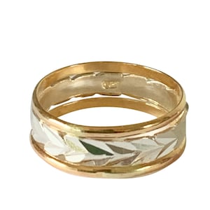 May include: A gold, silver, and rose gold band ring with a textured design.