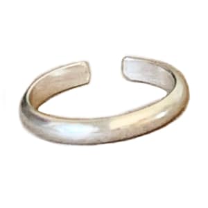 May include: A silver toe ring with a smooth, rounded surface.