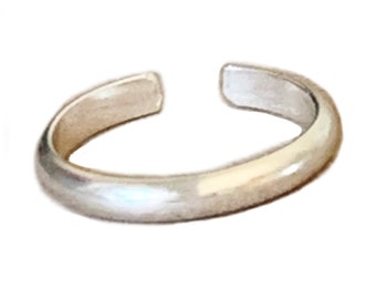 May include: A silver toe ring with a smooth, rounded surface.
