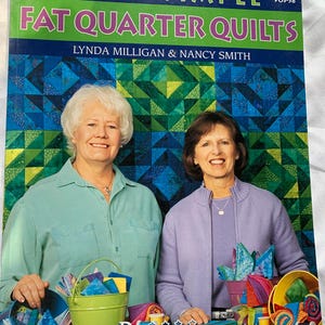 May include: A book cover titled "Super Simple Fat Quarter Quilts" featuring two women smiling. The cover has a blue, green, and white geometric pattern. The women are surrounded by colorful fabric and sewing supplies.