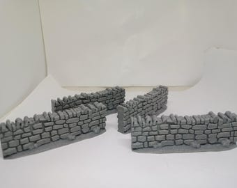 Puede incluir: Cuatro secciones de muro de piedra gris, cada una con una forma curva, diseñadas para su uso en juegos de miniaturas o construcción de modelos.