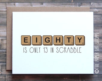 Puede incluir: Una tarjeta blanca con fichas de Scrabble marrones que deletrean "EIGHTY" con los valores numéricos en cada ficha. El texto debajo de las fichas dice "IS ONLY 13 IN SCRABBLE".