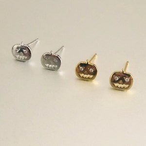 Può includere: Tre paia di orecchini a forma di zucca con un viso di jack-o'-lantern e piccoli strass trasparenti per gli occhi. Gli orecchini sono in argento, oro e oro rosa.