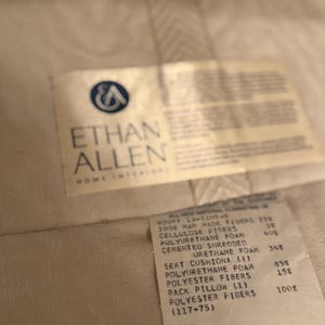 Puede incluir: Primer plano de una etiqueta de Ethan Allen Home Interiors. La etiqueta enumera los materiales utilizados en el producto, incluyendo fibras artificiales, fibras de celulosa, espuma de poliuretano y fibras de poli&eacute;ster.