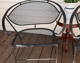 Par de sillas antiguas de hierro forjado con respaldo curvo.