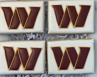 May include: Four sugar cookies decorated with white icing and a burgundy "W" with a gold outline.