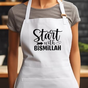 Puede incluir: Delantal blanco con texto negro que dice "Start with Bismillah" y dos pequeños corazones.