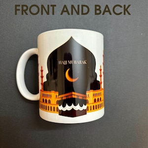 May include: White ceramic mug with a black and gold design featuring a mosque and the text "Hajj Mubarak".