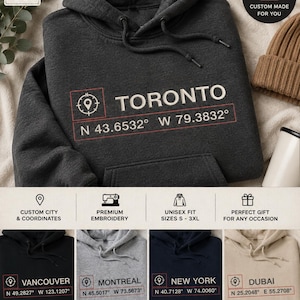 Peut inclure: Un sweat à capuche gris anthracite foncé avec une broderie blanche indiquant TORONTO, accompagnée d'un carré rouge contenant un symbole de boussole et les coordonnées N 43.6532 W 79.3832. Le sweat possède une poche kangourou sur le devant.