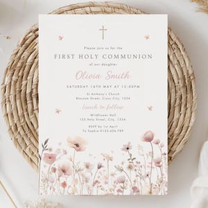 以下が含まれることがあります： 花柄のイラストが施された、最初の聖体拝領の招待状。「最初の聖体拝領」というテキストと「Olivia Smith」という名前が特徴です。デザインには、十字架と、ソフトピンクとグリーンのフローラルアクセントが含まれています。