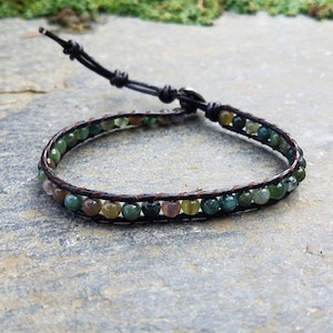 May include: A brown leather bracelet with green, brown, and white agate beads.