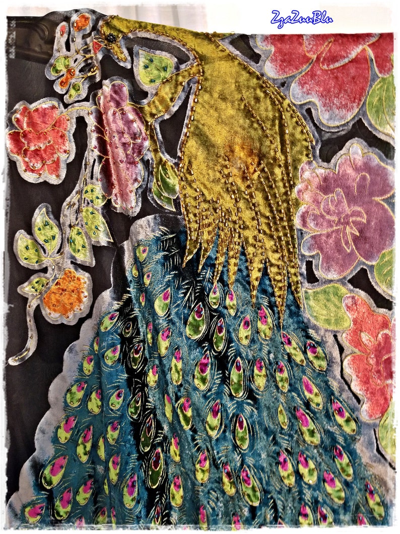 Puede incluir: Textil decorativo con dise&ntilde;o de pavo real. El cuerpo del pavo real es turquesa con detalles de plumas verdes y rosas. La cabeza y la parte superior del cuerpo son doradas, con detalles de cuentas. Elementos florales en rojo, rosa y verde rodean al pavo real.