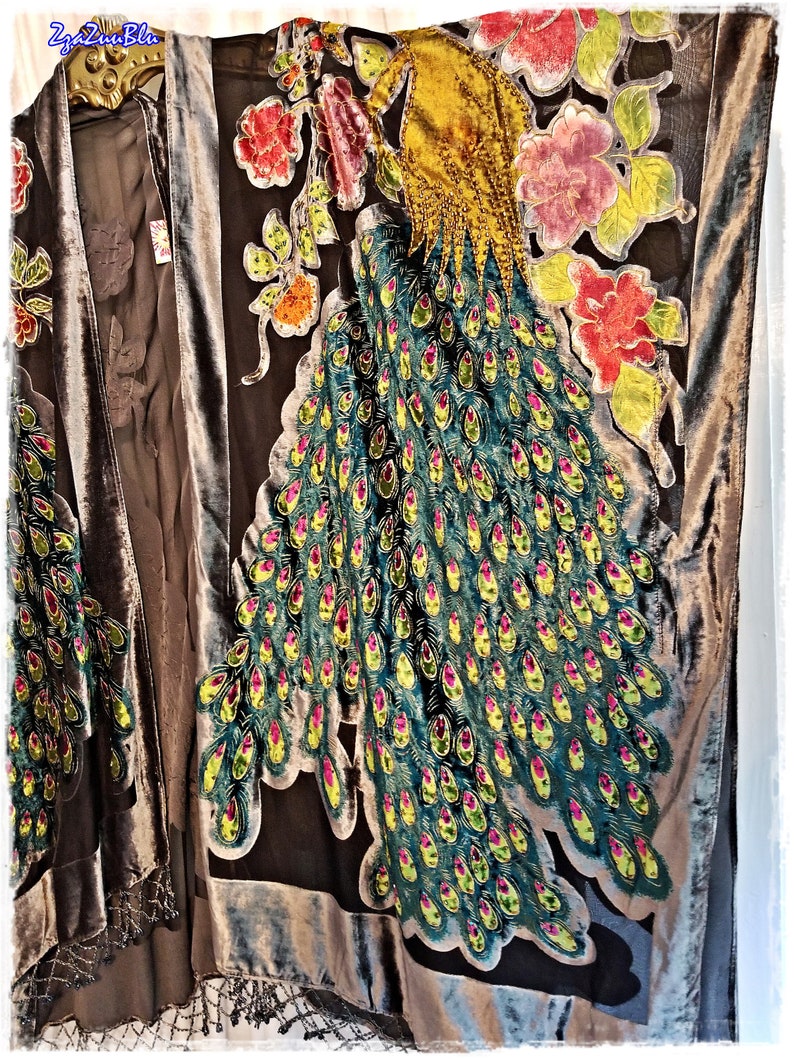 Puede incluir: Kimono de terciopelo marr&oacute;n oscuro con dise&ntilde;o de pavo real. El pavo real presenta una cabeza amarilla y plumas de cola verde azulado con detalles en rosa y amarillo. Tambi&eacute;n hay detalles florales en rojo, rosa y amarillo.