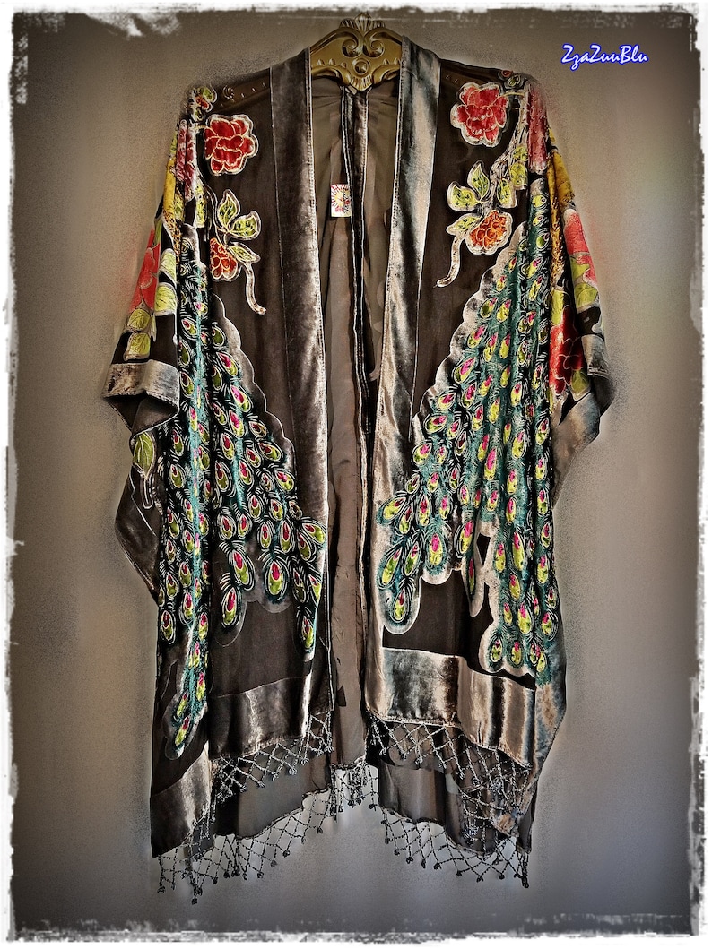 Puede incluir: Kimono de terciopelo gris con dise&ntilde;o de plumas de pavo real en tonos verdes, amarillos y rojos. El kimono tiene detalles florales y flecos de cuentas. El texto "2za2uuBlu" es visible en la esquina superior derecha.