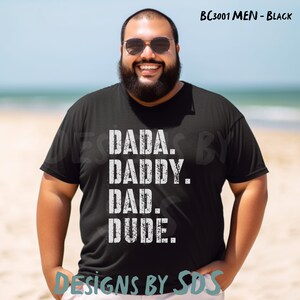 Può includere: Maglietta nera con una grafica bianca che dice "DADA. DADDY. DAD. DUDE."