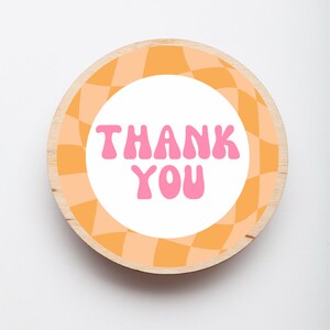 Puede incluir: Etiqueta redonda de madera para agradecer con un dise&ntilde;o a cuadros naranja y melocot&oacute;n. El texto "THANK YOU" est&aacute; en letras rosas.