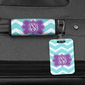 May include: A luggage tag and a luggage handle strap with a chevron pattern in turquoise and white. Both have a purple monogram with the letters "ISJ" in a decorative font.