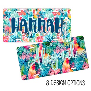 May include: Two colorful license plates with a tropical floral and rooster design. The top plate says "HANNAH" in dark blue lettering. The bottom plate says "Abigail" in light blue lettering.