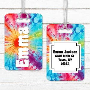 May include: Two tie-dye luggage tags. One tag has the name "Emma" in white letters. The other tag has a black and white box with the text "Emma Jackson 4321 Main St. Town, NY 01234".