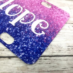 K&ouml;nnte beinhalten: Nahaufnahme einer glitzernden Nummernschild in Lila und Blau mit dem Wort "Hope" in Wei&szlig;.